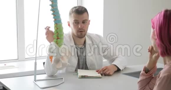 男医生正在用脊柱模型向病人解释治疗计划视频的预览图