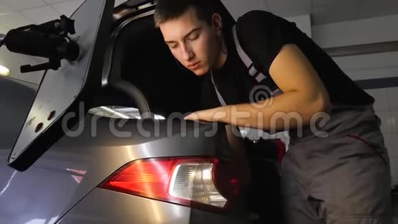 油漆无凹痕修补拆除PDR那家伙在一辆灰色汽车的后备箱里找东西视频的预览图