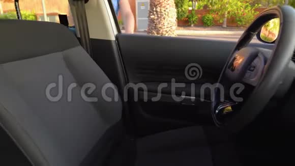穿着蓝色连衣裙的女人坐在车里系好安全带开车前把钥匙放进点火器里视频的预览图