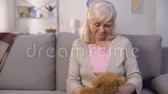 悲伤的老妇人抱着玩具泰迪熊失去了孙子长期分居视频的预览图