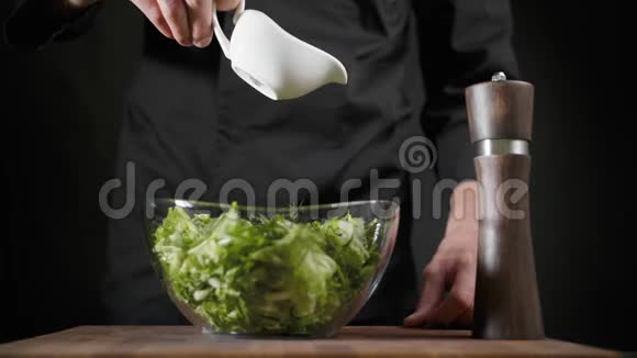 厨师将橄榄油倒入黑色背景的绿色沙拉中视频的预览图