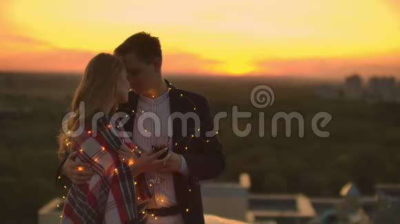 爱的夫妇坐在房子的屋顶上远处夜城的灯火视频的预览图