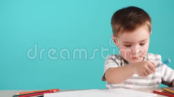 受启发的小男孩在桌子上用铅笔画画孤立在蓝色上视频的预览图
