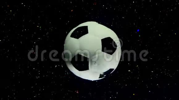 足球在黑色的太空星背景上绕着它的轴旋转有多种颜色的火花视频的预览图