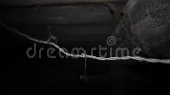 在黑暗的地下室里一根电线通向一个悬浮的白炽灯泡视频的预览图