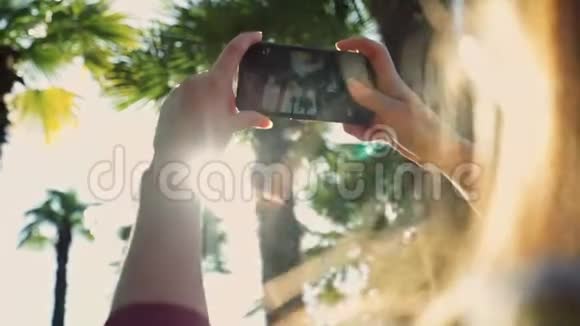 女孩在特写镜头中拍摄棕榈树智能手机的照片视频的预览图