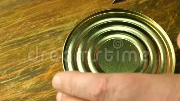 罐头肉人的手打开罐头炖罐用菜刀在木桌上特写镜头视频的预览图