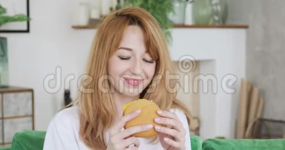 女人坐在家里的客厅里吃汉堡视频的预览图
