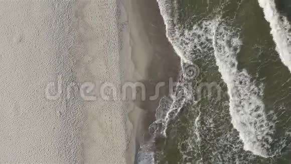 一股海浪冲向沙质海岸在沙滩上破碎视频的预览图