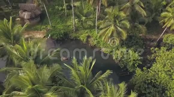 无人驾驶飞机在热带河流上空盘旋有漂浮的船和树叶视频的预览图