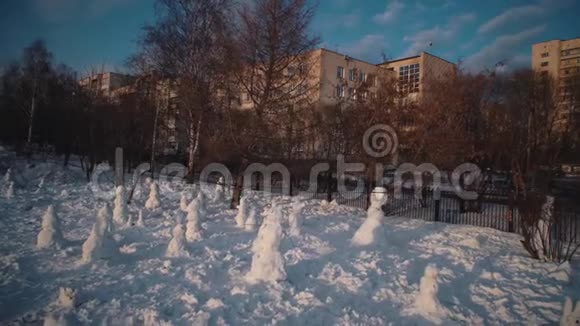 快乐的孩子在阳光明媚的冬日堆雪人视频的预览图
