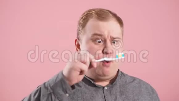 怀疑的男人手里拿着牙刷照顾牙齿健康视频的预览图