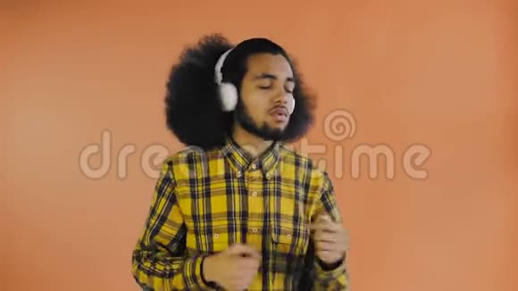 积极的非裔美国人听音乐在他的耳机橙色背景情感概念视频的预览图