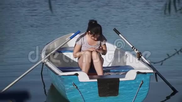 带着手机的年轻女孩坐在船上视频的预览图