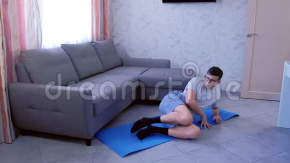 虚弱的书呆子在家里做腿躺在地板上的滑稽练习体育幽默概念视频的预览图