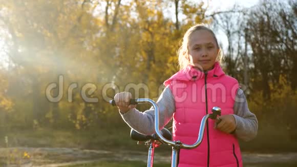 孩子们在公园里骑自行车旅行年轻女孩走路一个年轻女孩沿着马路散步骑自行车视频的预览图