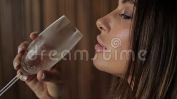一个美丽的女人从玻璃侧面喝香槟的肖像视频的预览图
