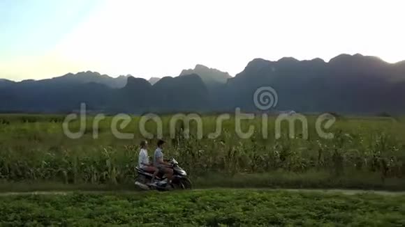 女孩和男人骑着摩托车在日落鸟瞰的田野视频的预览图