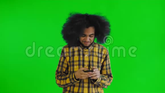 美国黑人卷发男子在智能手机上绿色屏幕或色度键背景上聊天的肖像视频的预览图