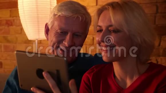 一对年长的幸福夫妇在平板电脑上打了一个视频电话坐在沙发上愉快地交流着视频的预览图