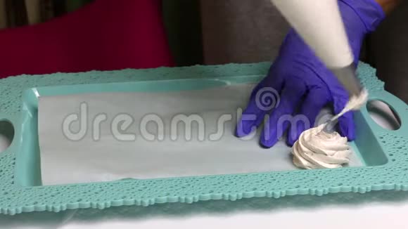 一个女人用一个糕点包做白色棉花糖棉花糖放在托盘上视频的预览图