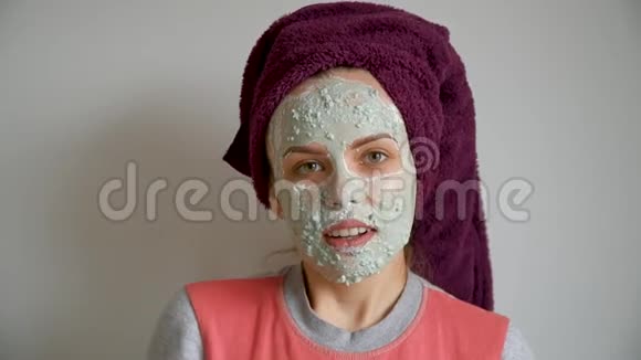 美丽的女孩从面部皮肤上去除化妆品绿色剥皮面具的肖像女孩很惊讶视频的预览图