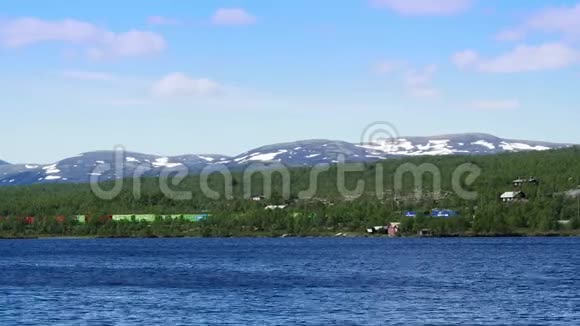 五颜六色的货运列车沿着美丽的湖泊和山腰景观的遥远海岸经过视频的预览图