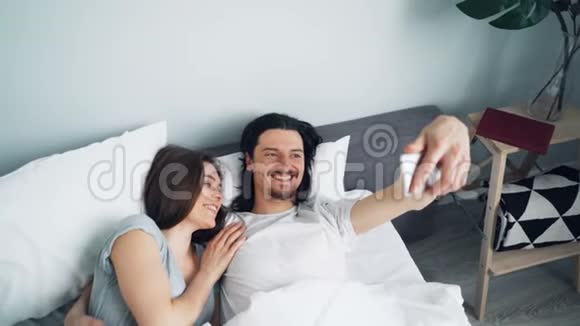 女孩和男人在床上自拍智能手机摄像头亲吻拥抱视频的预览图
