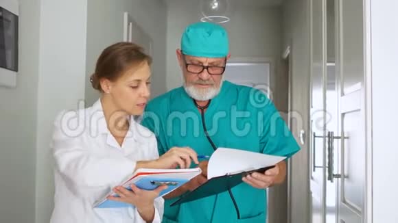 成熟的男性外科医生在医疗诊所的走廊里给护士指路手术准备视频的预览图