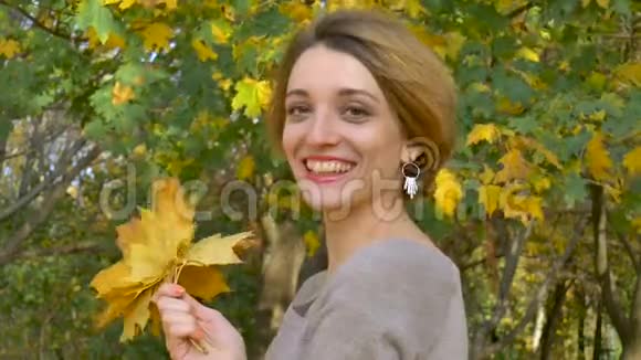 一位有着迷人情感的年轻女子她留着一头金发穿着一件紧身连衣裙上面挂着一束秋叶视频的预览图