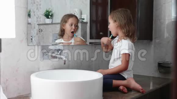 小女孩正在镜子前用牙刷刷牙视频的预览图