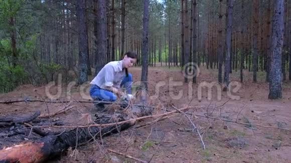 森林野营的年轻女子用斧头砍树干当柴视频的预览图
