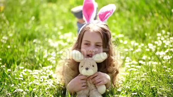 可爱的小兔子耳朵躺在草地上复活节那天小女孩在春天的花园里玩耍传统的庆祝活动视频的预览图