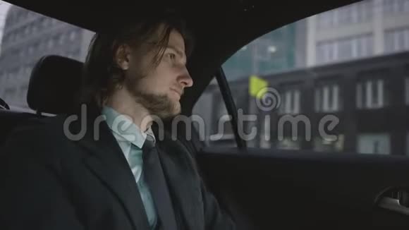 棕色头发的帅哥穿着开心果衬衫灰色西装乘车系安全带视频的预览图