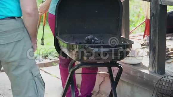 一个男人在烧烤炉里烧煤一个女人用钳子调整煤视频的预览图