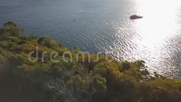 海底浮船在背景阳光反射水面上石上的绿岛和海浪视频的预览图