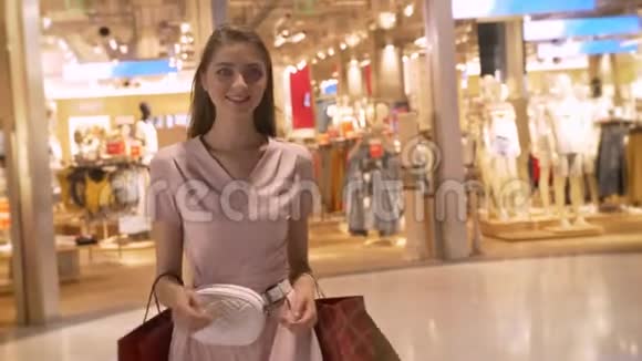 年轻有魅力的女孩去商场购物拿着袋子微笑购物观念时尚观念视频的预览图