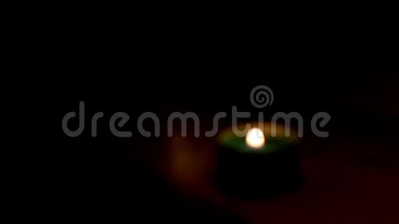 茶烛火焰聚焦在木桌上的黑暗房间里视频的预览图