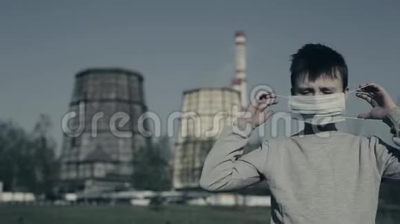 小男孩把污染面罩放在工厂烟囱上看着相机空气污染概念视频的预览图