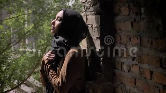 年轻的穆斯林妇女戴着黑色头巾手挽手向上看站在废弃的砖楼里视频的预览图