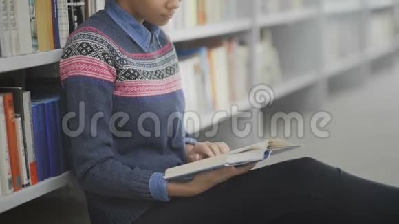 非裔美国妇女多利搬家正坐在学校图书馆的地板上看书视频的预览图