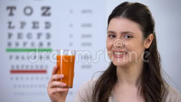 快乐的女人喝健康的新鲜胡萝卜汁背景视觉视频的预览图