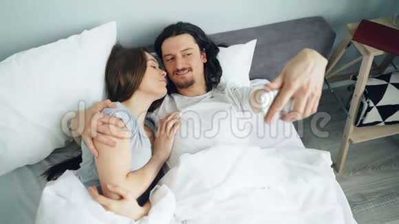 夫妻俩用智能手机拍照在床上拥抱视频的预览图