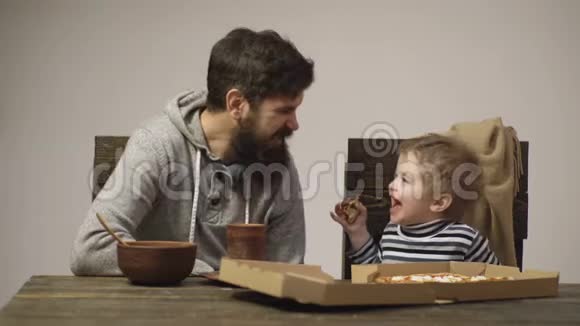 长胡子的男人和一个小男孩吃比萨饼在白色背景下互相尖叫小男孩在吃一片视频的预览图