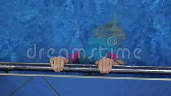 小女孩正在游泳池里潜水手握金属扶手视频的预览图