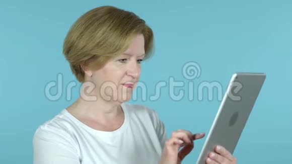 老女人通过蓝底平板电脑进行视频聊天视频的预览图