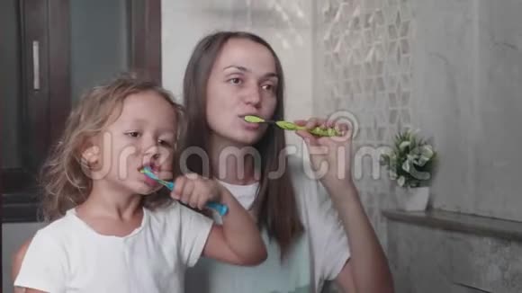 妈妈和她可爱的小女儿正在一起用牙刷刷牙视频的预览图