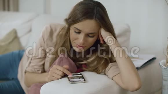 年轻女子在家里滚动电话使用智能手机的幸福女人亲密无间视频的预览图