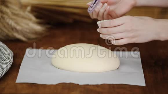 贝克为烤箱准备面包女人在生面包上刷熔化的黄油视频的预览图