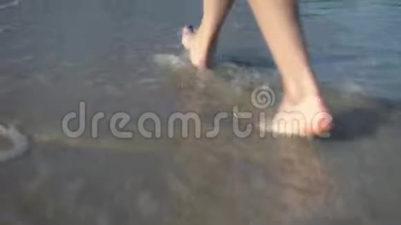 一个女人在沙滩上散步双腿合拢海浪涌到海边视频的预览图